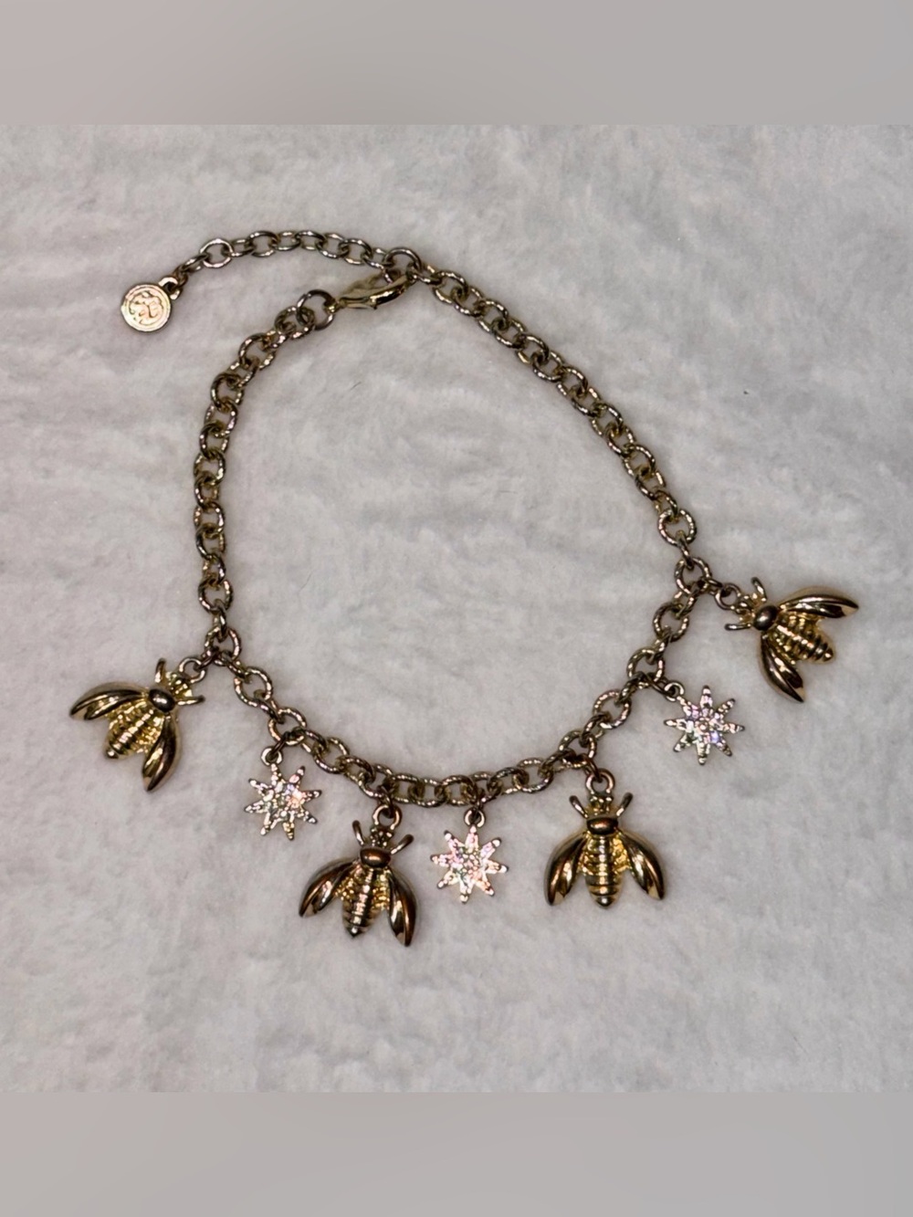 Gold charm bracelet features alternating bee charms & sparkling star charms